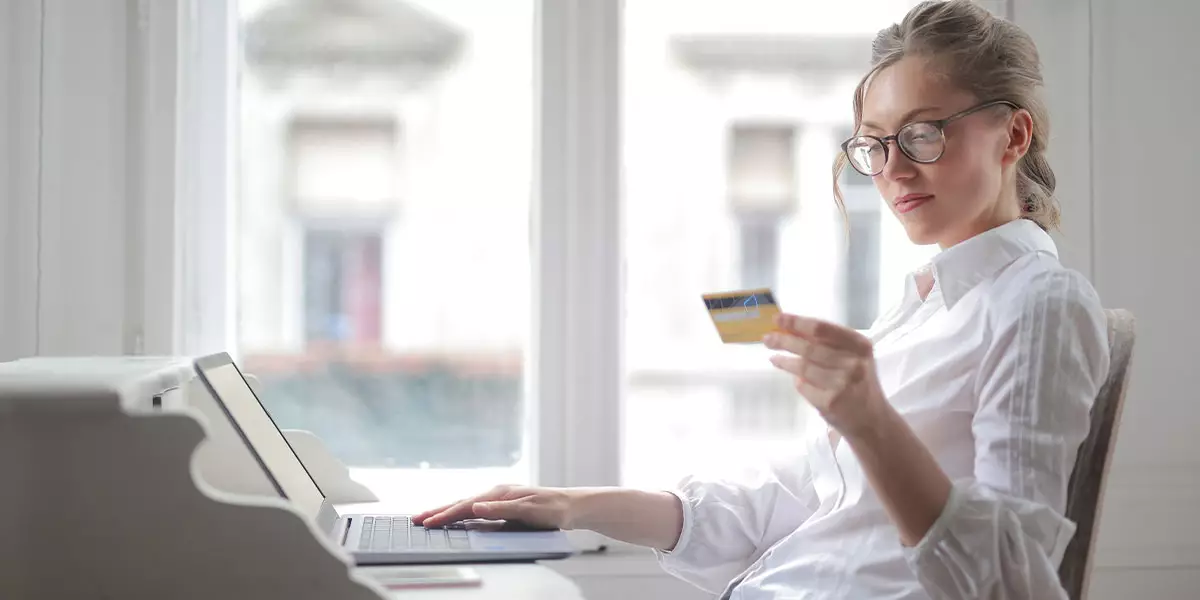 A-person-holding-their-phone-or-sitting-at-their-computer-with-a-debit-credit-card-in-hand