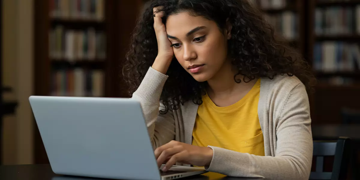 A-person-sitting-at-a-computer-with-a-bored-expression-on-their-face