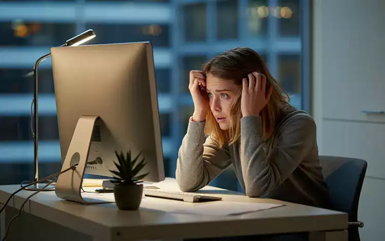 A-person-sitting-in-front-of-a-computer-and-tugging-at-their-hair-in-frustration