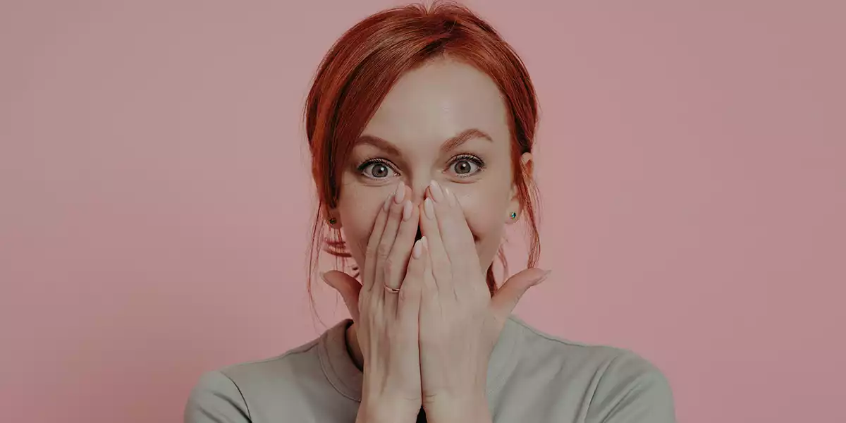 Close-up-of-a-person-with-their-hands-over-their-mouth-to-avoid-talking