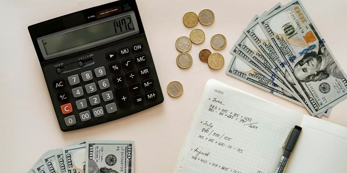 Money-laid-out-across-a-table-alongside-a-notepad-or-calculator