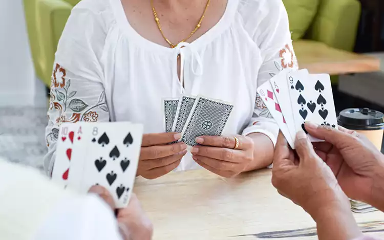 adults gambling on a table with cards in their hands