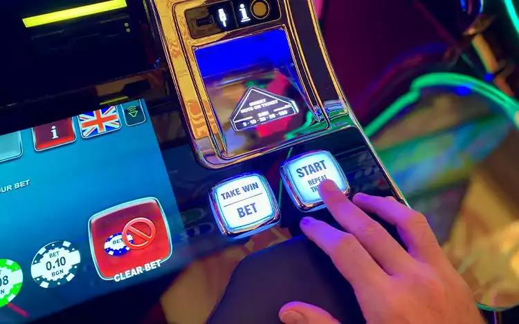 Finger on start button on Casino Slots Machine