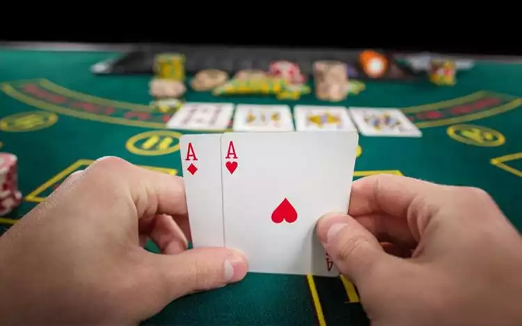 Person holding playing cards beside chips