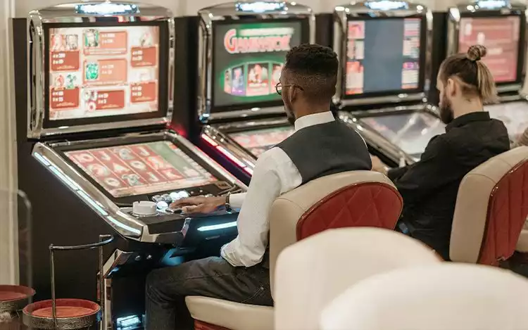 a man playing a video game in front of a row of slot machines.