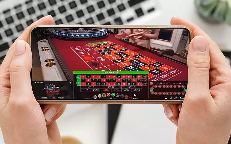 a casino player engaged in an online american roulette on his mobile device.