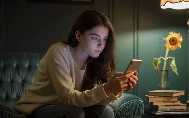 sad woman sitting on the couch, using the phone
