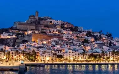 Night view in Ibiza illuminated by dazzling lights and the glow of the moonlit sea.