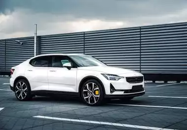 Side shot of 5-door white 4x4 vehicle with modern features, parked in a bayed car park with an iron corrugated wall in the background. Overlooking a partially cloudy sky