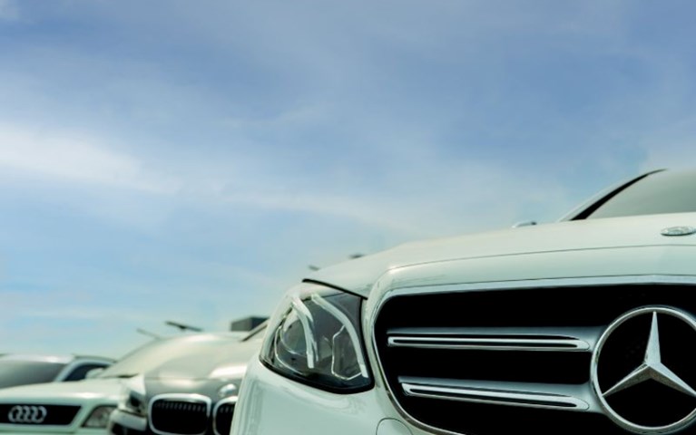 A white Mercedes car, black BMW and white Audi parked in a row under a blue sky