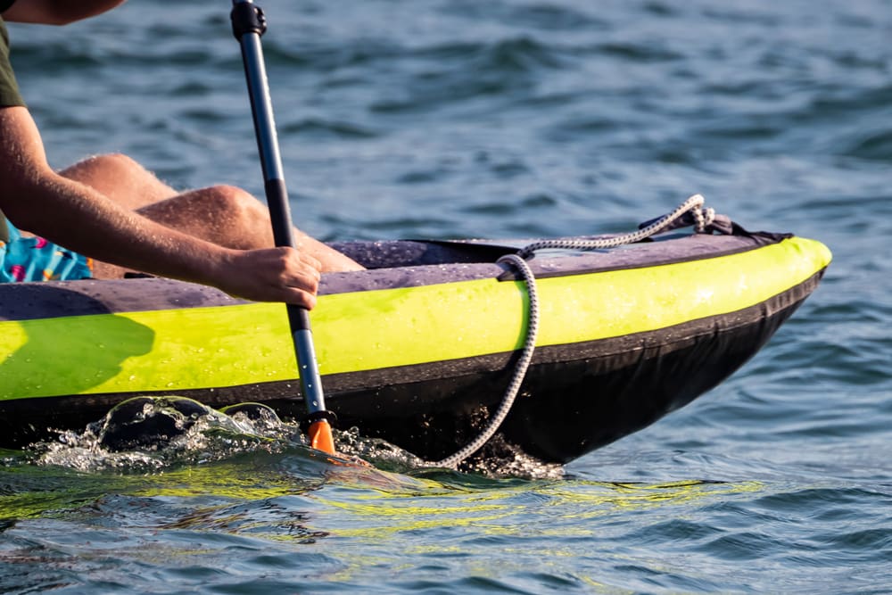 Someone paddling in a neon yellow and black canoe in Lake Como