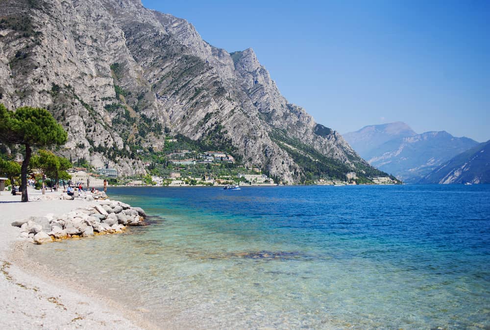 View of big blue lake from the shoreline with mountains in the background