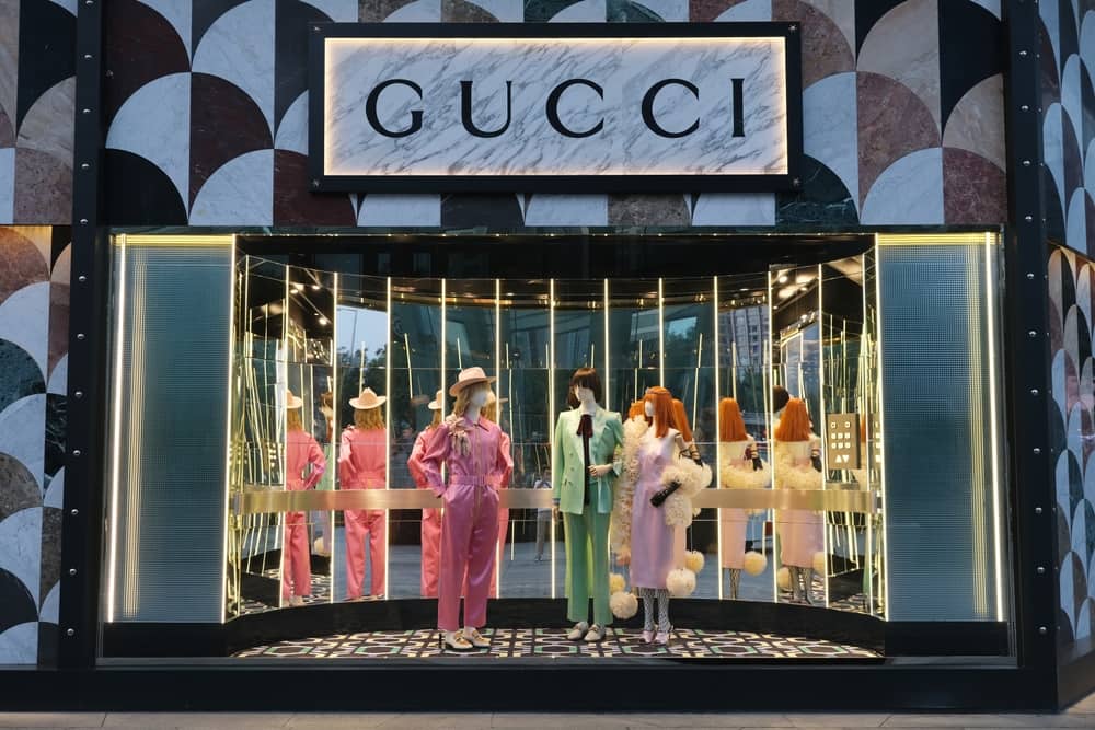Gucci store window with three mannequins with multiple mirrors behind them