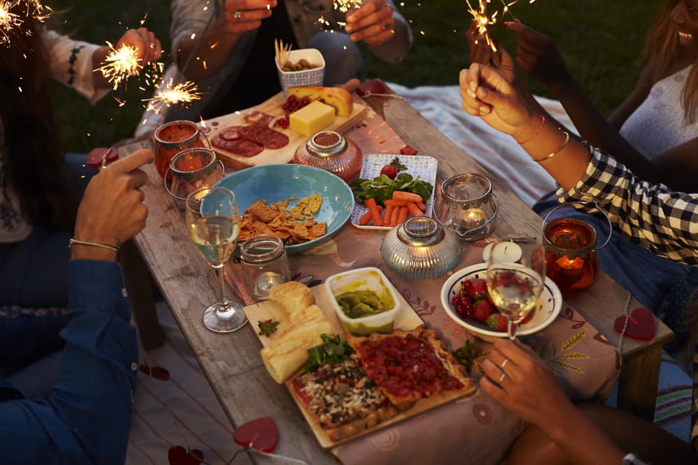 People sat round a table of food holding sparklers