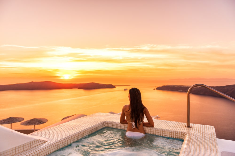 Person in a jacuzzi looking out at the sea and sunset