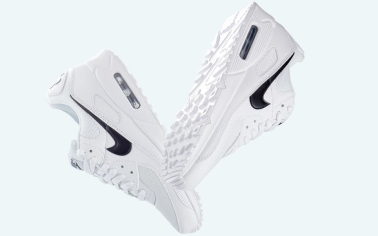 Clean white trainers facing downwards with padded soles with a black swoosh pattern on the sides