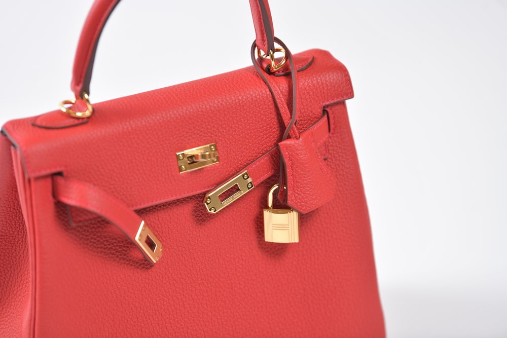 Close-up picture of a red Kelly bag, which feature gold detailing, including a clasp and padlock