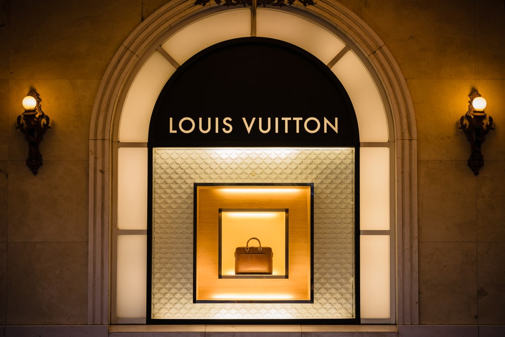 Shop window showcasing a Louis Vuitton handbag with yellow backdrop