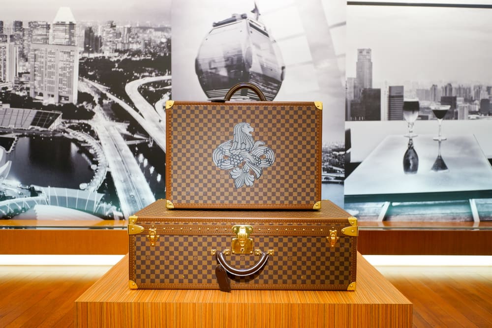 Two Louis Vuitton suitcases neatly displayed on a wooden podium with a mural of black and white photography behind