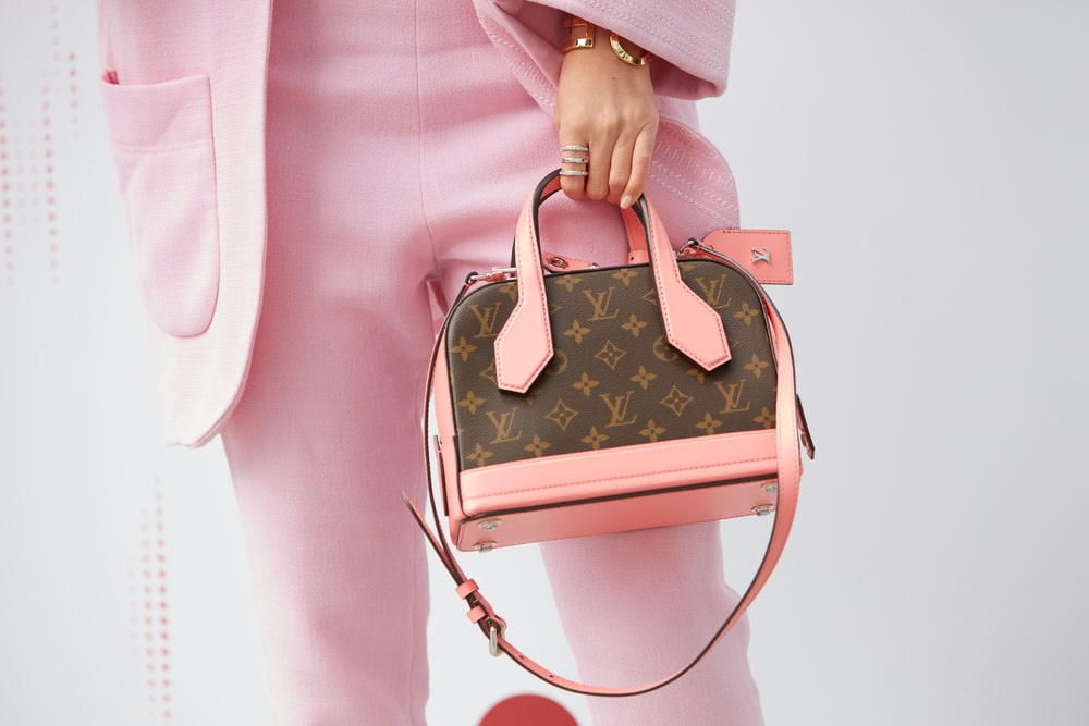 Person wearing a light pink suit holding a Louis Vuitton bag with light pink accents