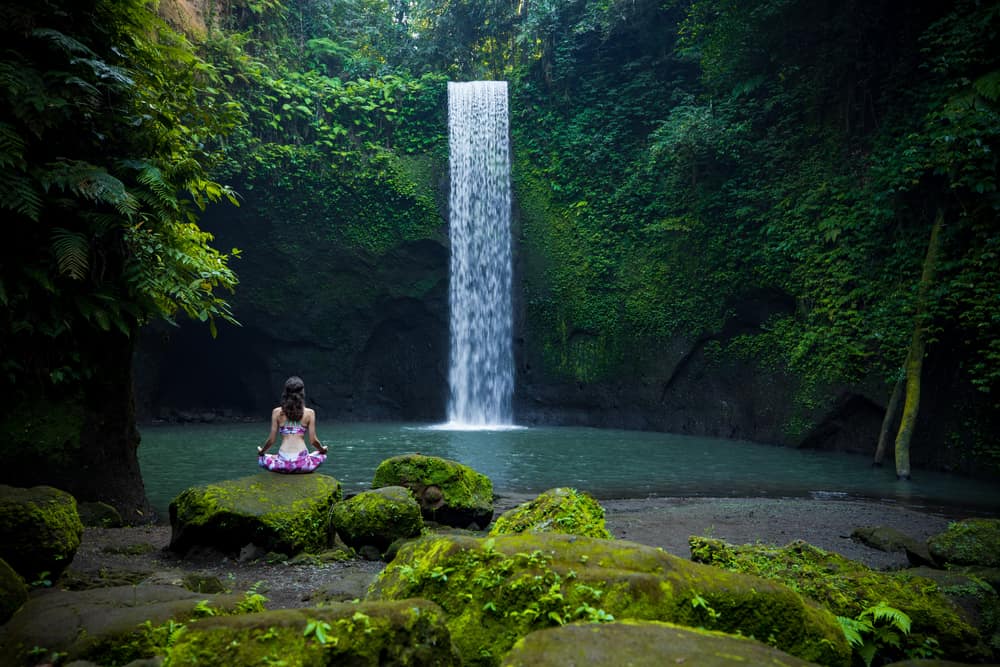 Woman doing Yoga near the Tibumana waterfall in Bali