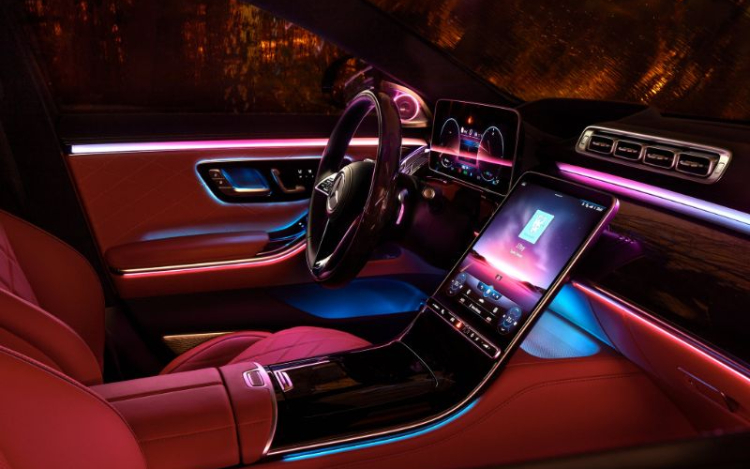  interior of the front of a Mercedes Benz car, with red seats, a mahogany-style dashboard and steering wheel