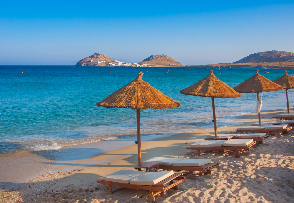 A sandy beach near the blue sea with sun beds and umbrellas