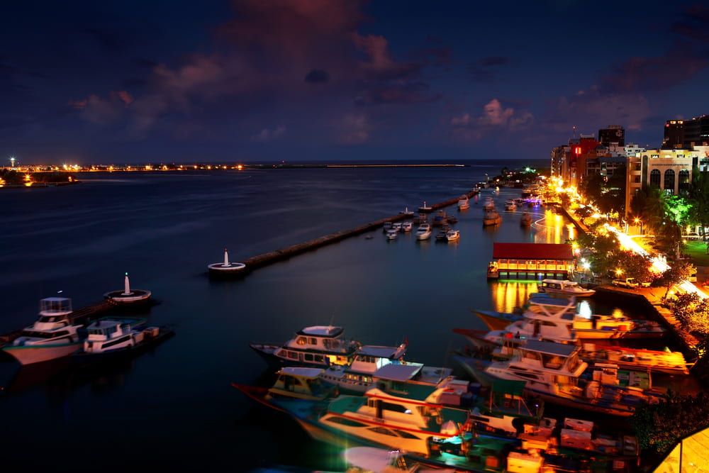 Evening panorama of jetty with boats and the street of Male with bright orange lights