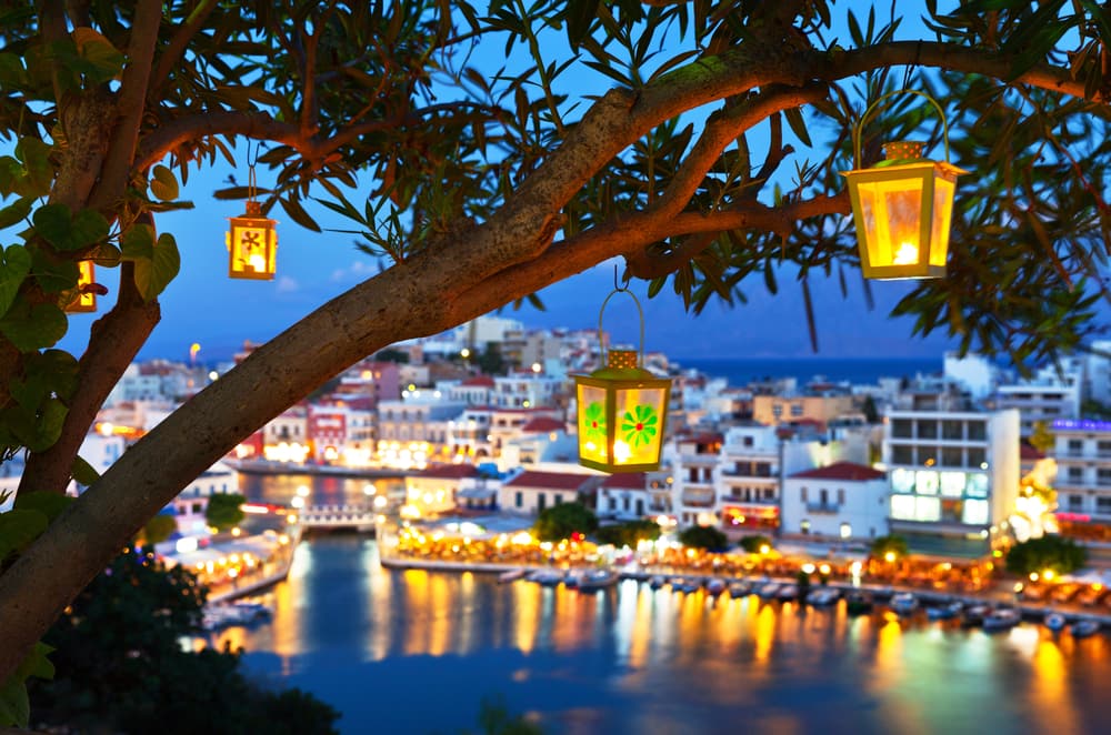 Evening view of the town of Agios Nikolas, Crete, under a tree with lanterns