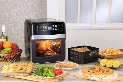 High-end air fryer with a whole roast chicken inside, a basked of fruit to the left, in front is an array of cooked foods and vegetables and to the right is a basket of fried chicken.