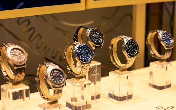 Omega watches displayed on individual clear plastic stands under warm yellow lighting in an Omega shop