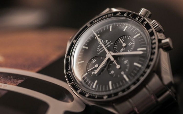 A silver Omega watch with a navy blue face resting on a counter