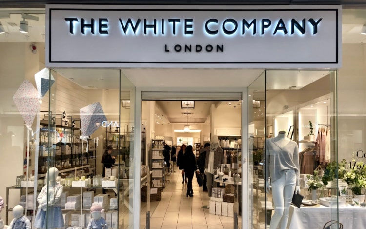 The White Company storefront, with glass windows, the brand logo above the door in black writing on a white background