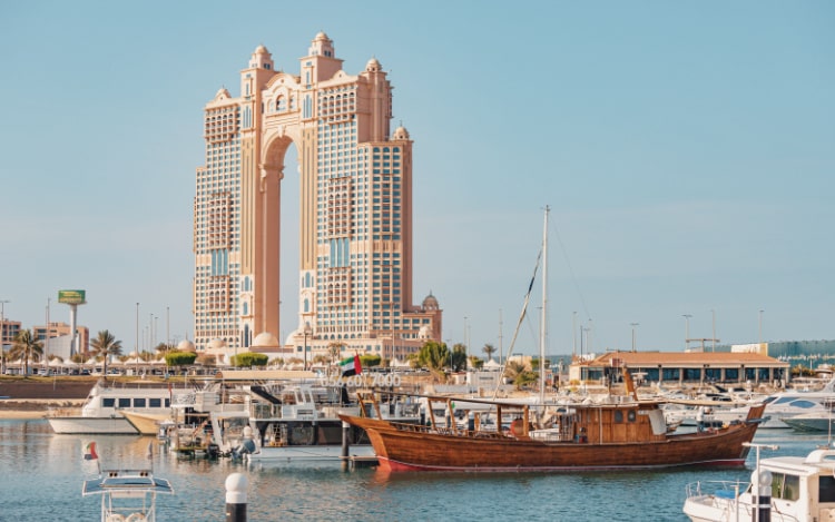 A view of Rixos Marina majestic palace hotel from the port, with cruise boats and ships in the foreground floating on the water.