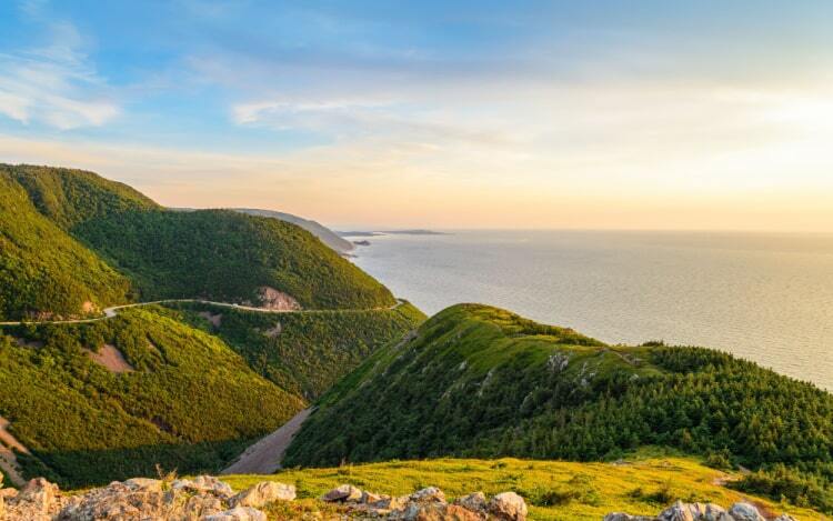 Grassy hills at sunset with a view to the sea.