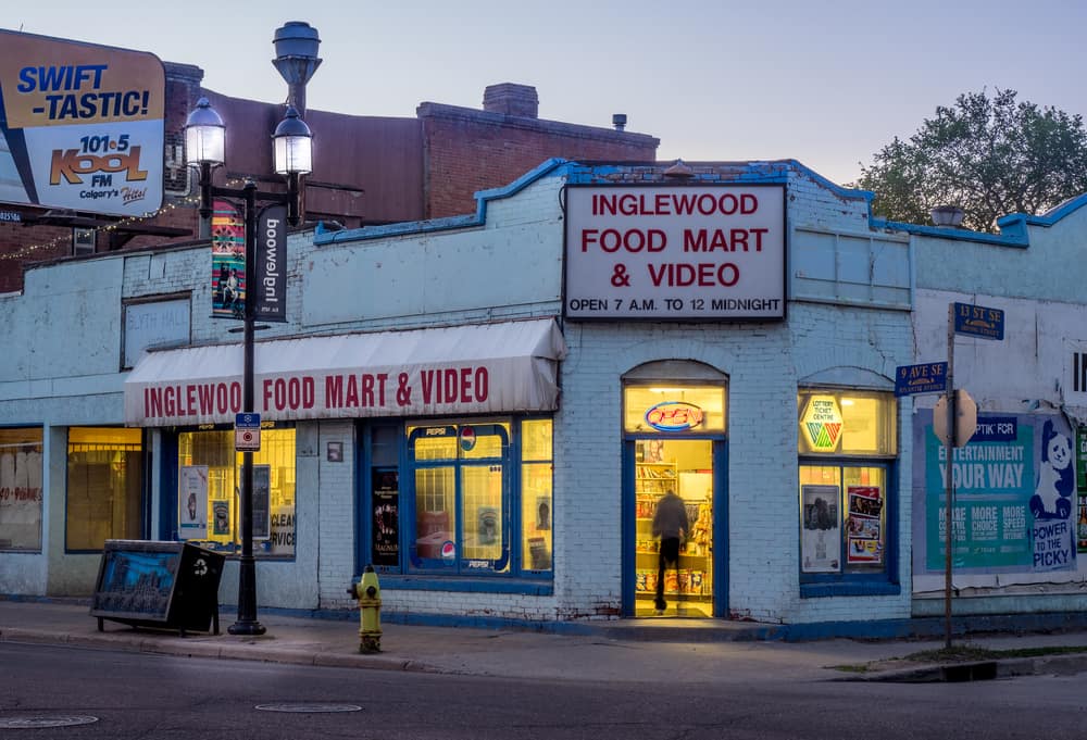 Street view of Inglewood Food Mart & Video store in the evening with bright yellow lighting