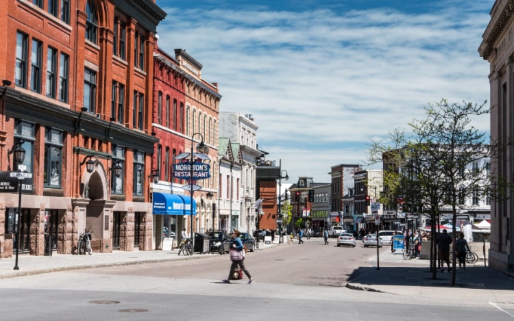 A high street in Kingston with shops and businesses lining the street. A shopper is crossing the road to the left-hand side.