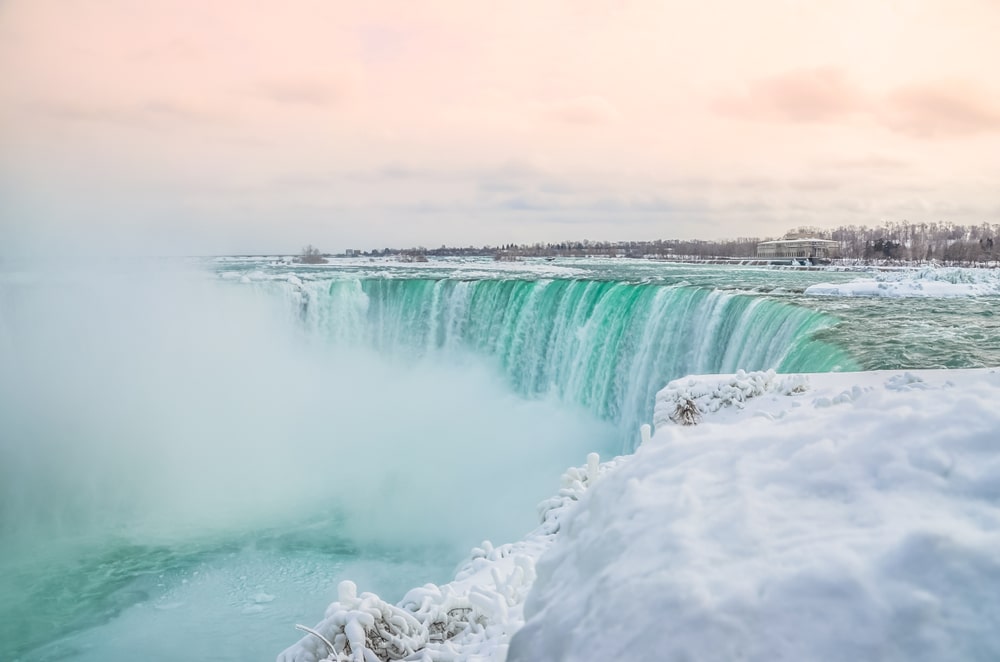 Winter waterfall with peach-coloured sky