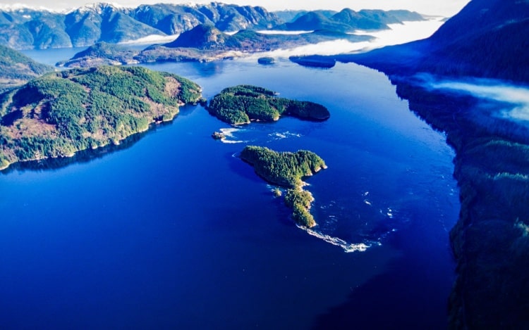 Aerial view of the island surrounded by deep blue sea and mountains.
