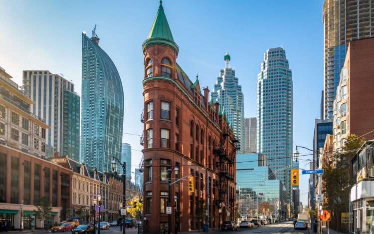 A cluster of skyscrapers and red brick buildings in Toronto under a clear blue sky.