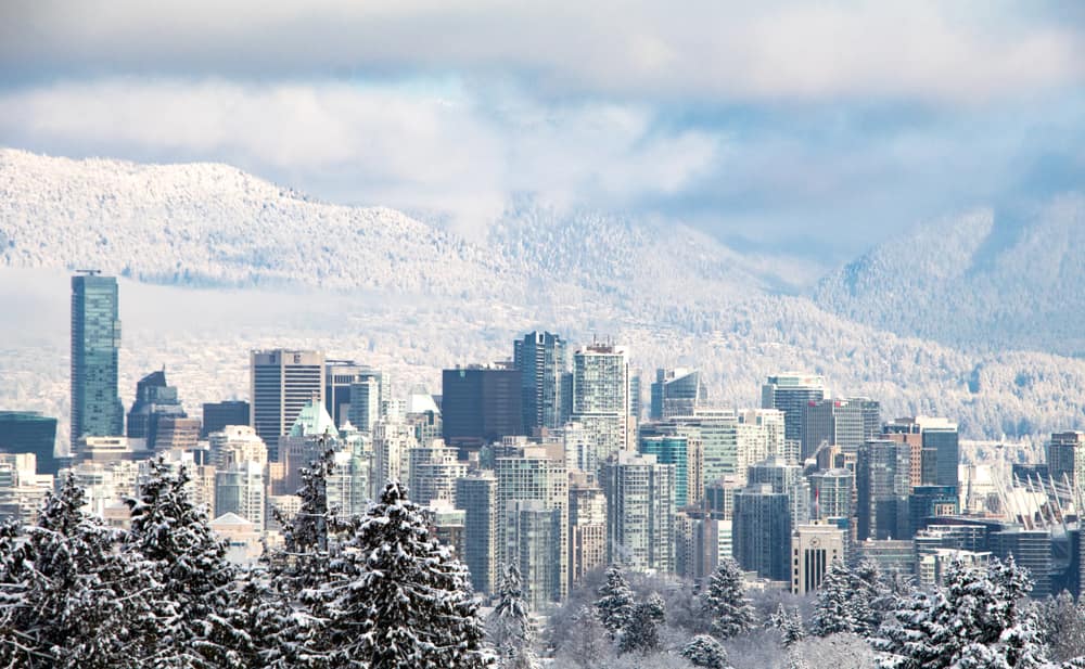 Cityscape view of Vancouver downtown. Tall business building and tower in snow day in winter with mountain view