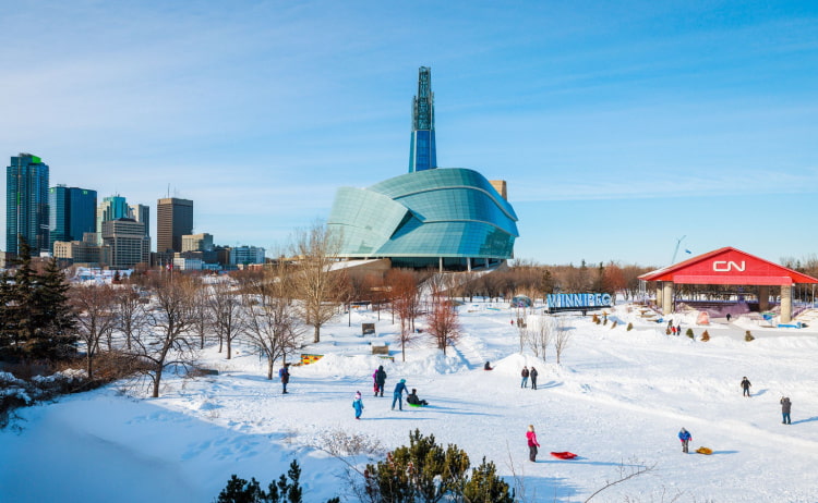 Winnipeg in winter with a clear blue sky and skyscraper backdrop and snow-covered ground