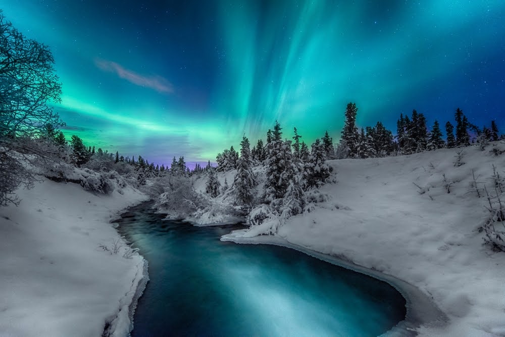 Northern lights with water and snowy terrain