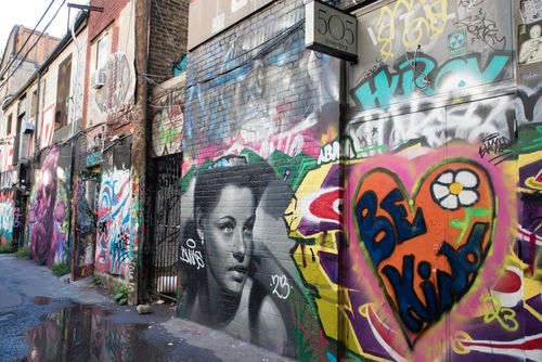 A shot of the art in Graffiti Alley, Toronto. A black and white painting of a woman’s face can be seen in the centre.