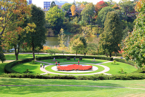 A high view of High Park in Toronto. You can see a maple leaf floral design in the centre of the park and people walking around it.