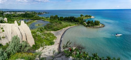 A high view of Scarborough Bluffs. You can see the striking mountains, busy coastline and blue waters from above.