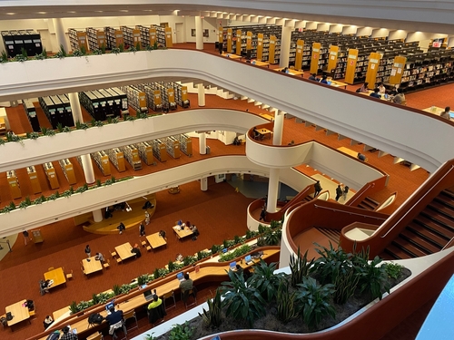 A high view of the interior of Toronto Reference Library. You can see people working amidst shelves filled with books.